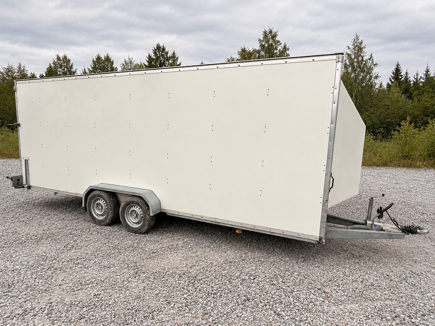 Side view of the enclosed trailer with tandem wheels and front coupling